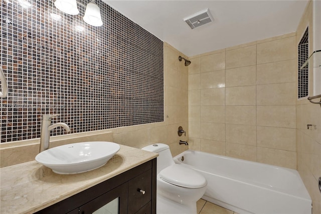 bathroom featuring vanity, toilet, tile walls,  shower combination, and visible vents