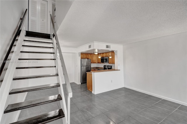 stairway with baseboards, tile patterned flooring, a textured ceiling, and visible vents