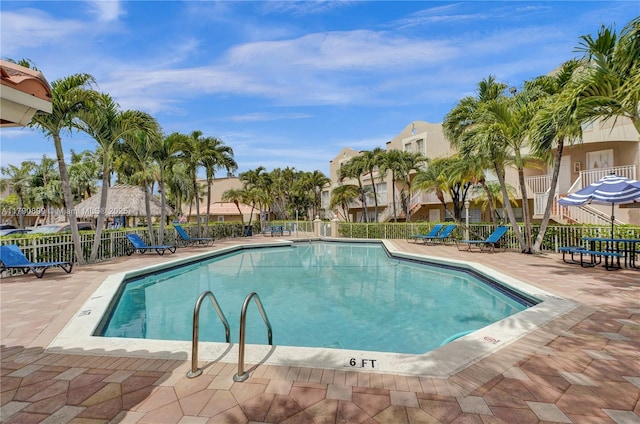 community pool featuring fence, a residential view, and a patio area