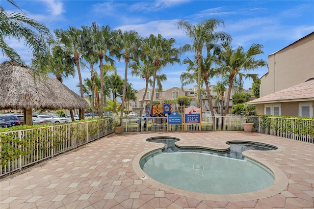 pool with a jacuzzi, fence, playground community, and a residential view