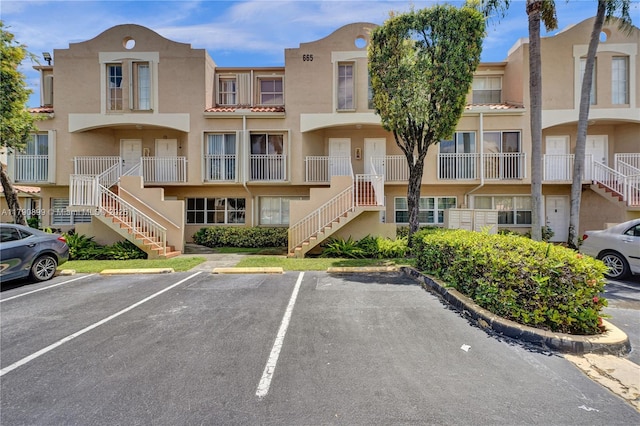 view of property with uncovered parking and stairs
