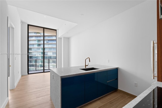 kitchen with a peninsula, baseboards, modern cabinets, a sink, and light wood finished floors