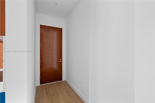 hallway featuring baseboards and light wood-type flooring