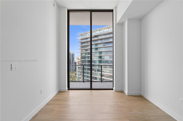 empty room featuring a healthy amount of sunlight, expansive windows, and wood finished floors