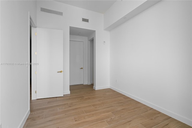 spare room featuring visible vents, light wood-style floors, and baseboards