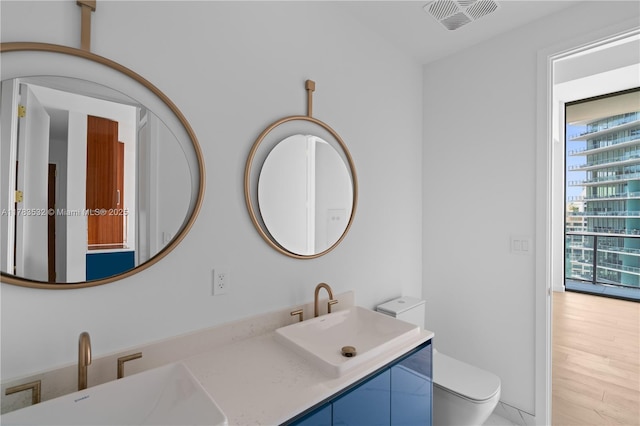 bathroom featuring double vanity, toilet, visible vents, and a sink