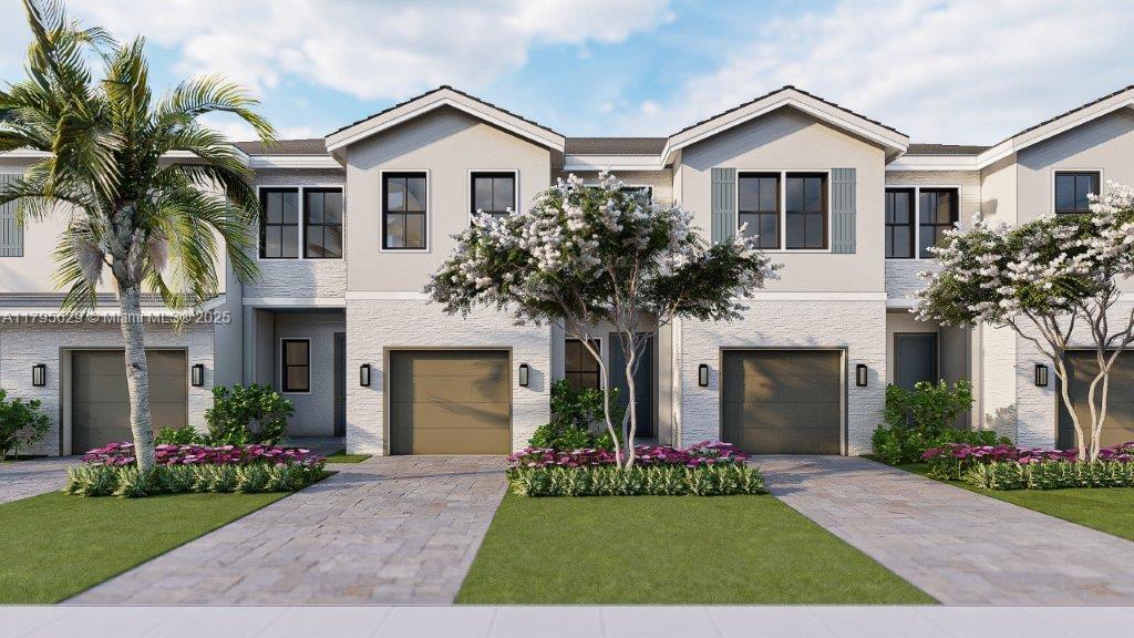 townhome / multi-family property with a front yard, stucco siding, and an attached garage
