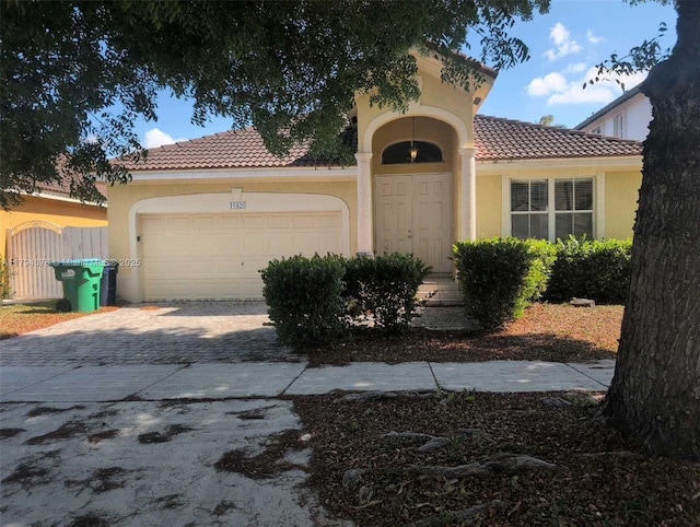mediterranean / spanish house with a garage, stucco siding, driveway, and a tile roof