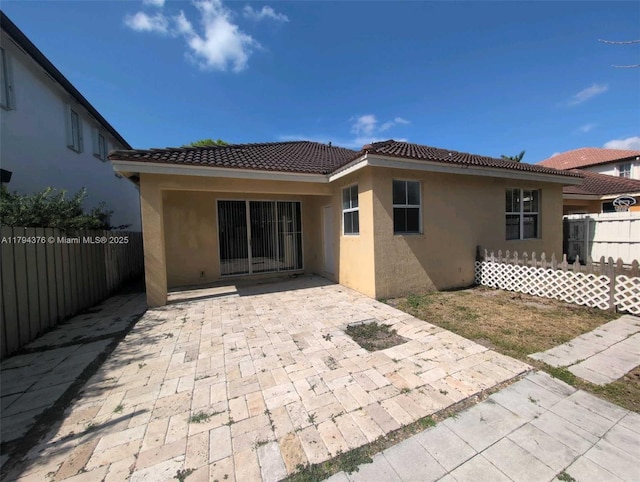 back of property featuring a patio, a tile roof, fence private yard, and stucco siding
