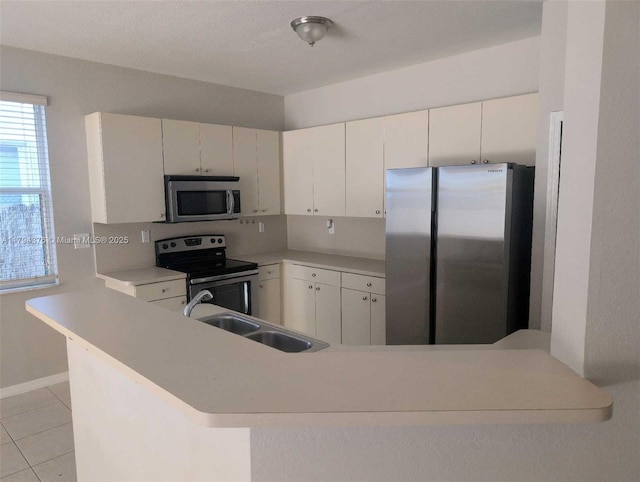 kitchen featuring appliances with stainless steel finishes, a sink, light countertops, white cabinets, and light tile patterned flooring