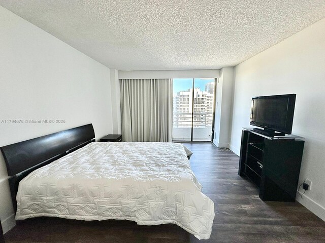 3300 NE 192nd St Unit Ph09, Aventura, FL 33180 - bedroom featuring dark wood-style flooring, baseboards, a textured ceiling, and access to outside