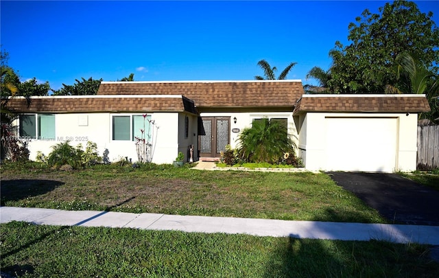 view of front of property featuring a garage, aphalt driveway, a front yard, mansard roof, and a shingled roof