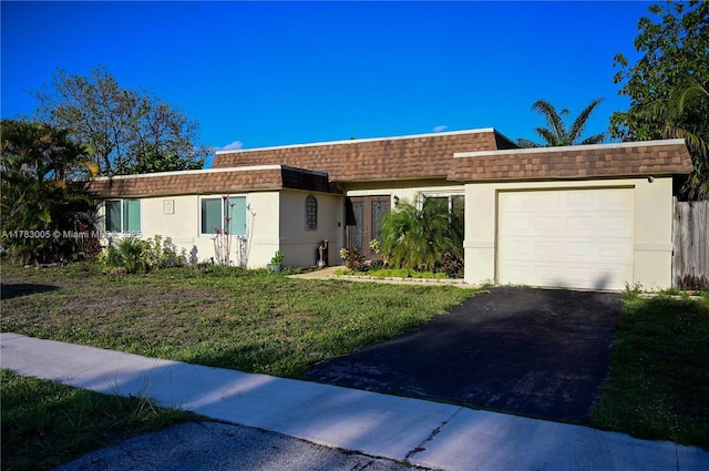 single story home featuring aphalt driveway, a front yard, stucco siding, a shingled roof, and an attached garage