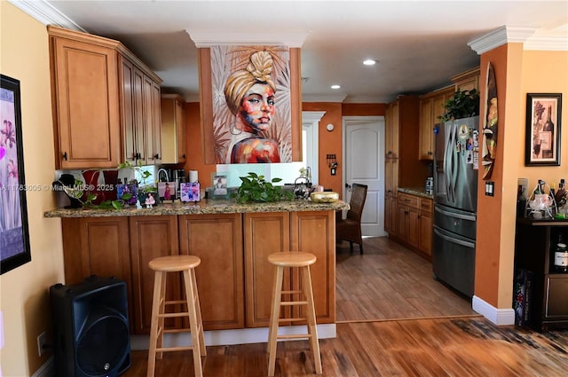 bar with ornamental molding, wood finished floors, baseboards, stainless steel fridge, and recessed lighting
