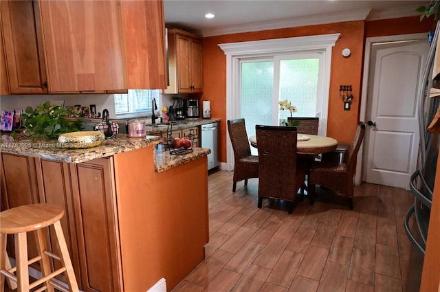 kitchen with a peninsula, brown cabinetry, a wealth of natural light, and light wood-type flooring