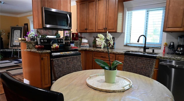 kitchen with range with electric stovetop, brown cabinets, dishwasher, a sink, and stainless steel microwave
