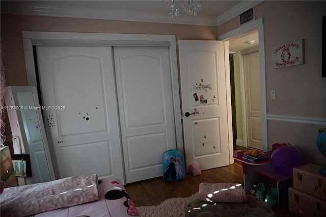 bedroom with crown molding, visible vents, wood finished floors, and a closet