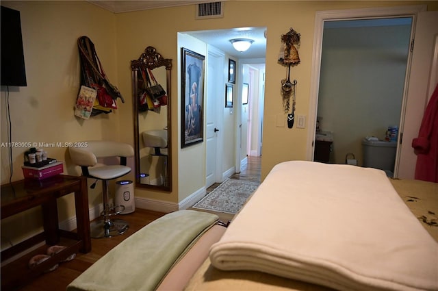 bedroom with baseboards, visible vents, and wood finished floors