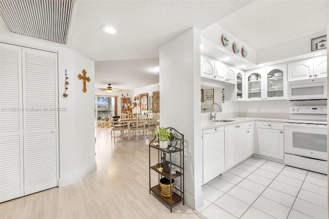 kitchen featuring a sink, white appliances, light countertops, visible vents, and glass insert cabinets