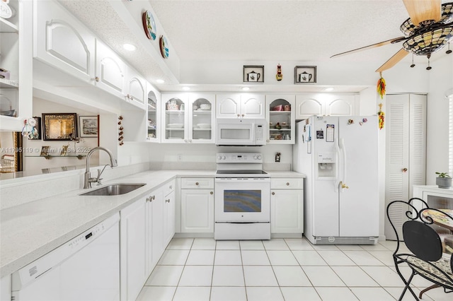 kitchen featuring white appliances, a ceiling fan, glass insert cabinets, and a sink