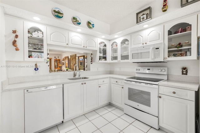kitchen with white appliances, white cabinetry, glass insert cabinets, and a sink