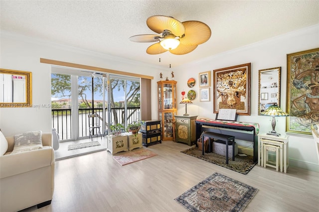 living area featuring crown molding, ceiling fan, a textured ceiling, wood finished floors, and a water view