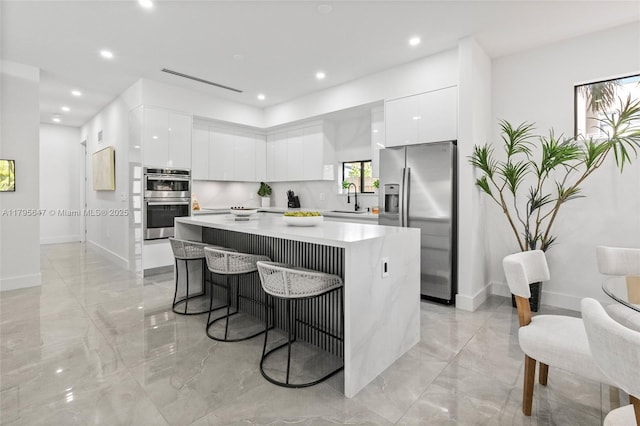 kitchen with stainless steel appliances, modern cabinets, a sink, light marble finish floors, and recessed lighting