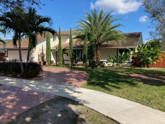 view of front of house with a garage, a front lawn, and stucco siding