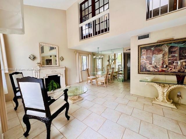 interior space featuring visible vents, a high ceiling, a fireplace, and an inviting chandelier
