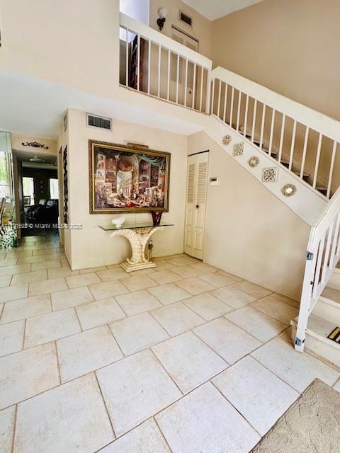 staircase with visible vents, tile patterned floors, and a high ceiling