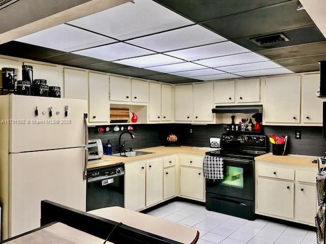 kitchen featuring a sink, light countertops, black appliances, under cabinet range hood, and light tile patterned flooring