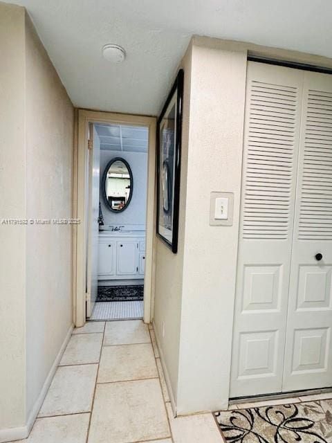 hall featuring light tile patterned floors and baseboards