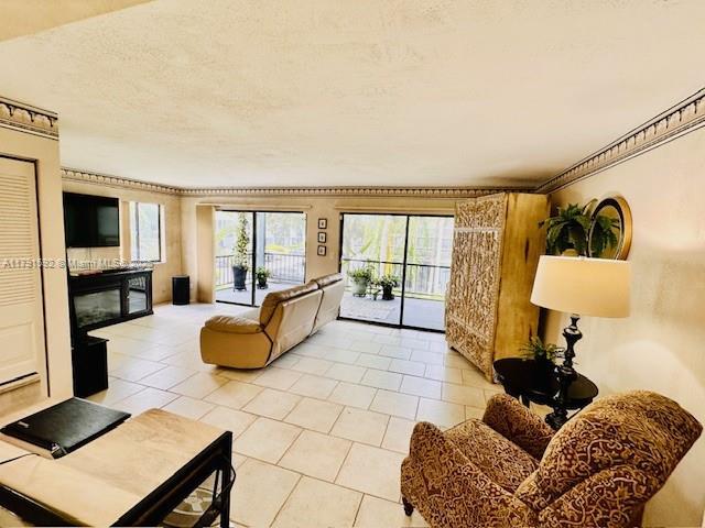 living room with a textured ceiling, a glass covered fireplace, and light tile patterned floors
