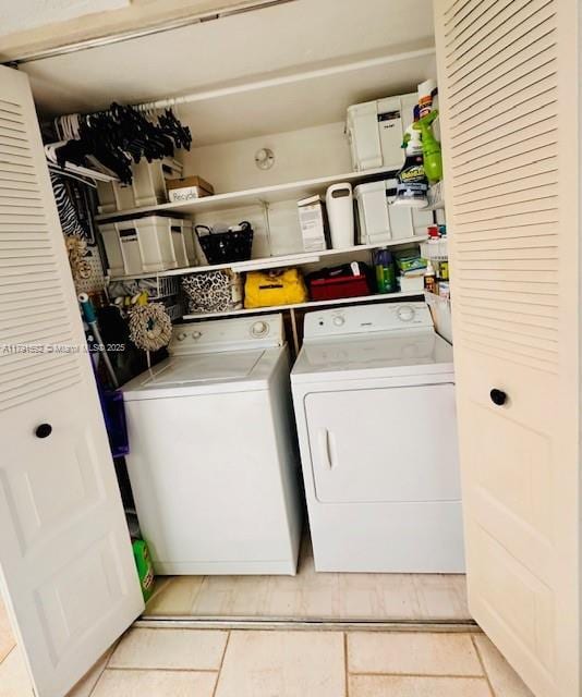 washroom featuring laundry area, light tile patterned flooring, and washing machine and clothes dryer