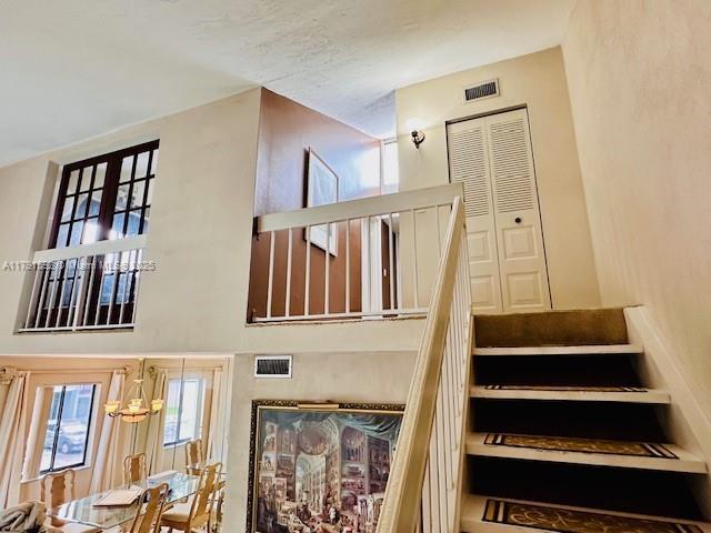 stairs featuring visible vents and a towering ceiling