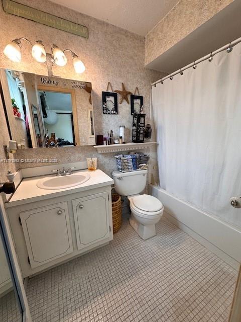 full bath featuring toilet, shower / bath combination with curtain, and vanity