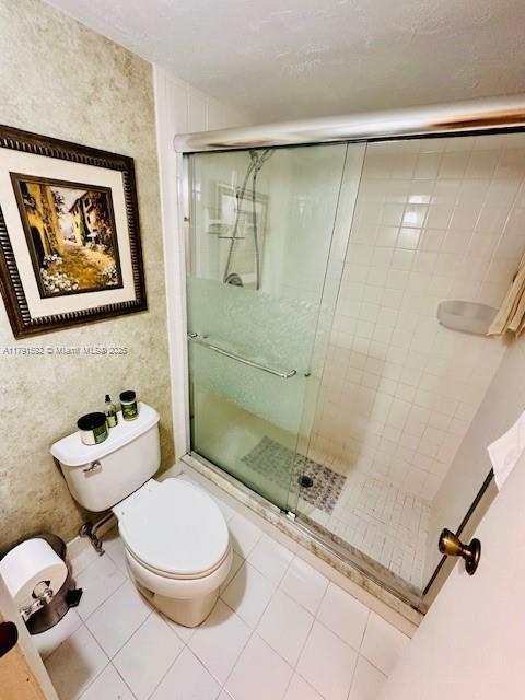 full bath featuring tile patterned flooring, a stall shower, and toilet