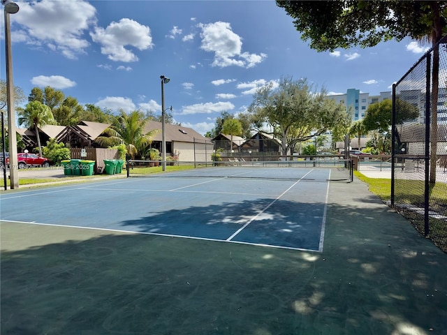 view of tennis court featuring fence and a residential view