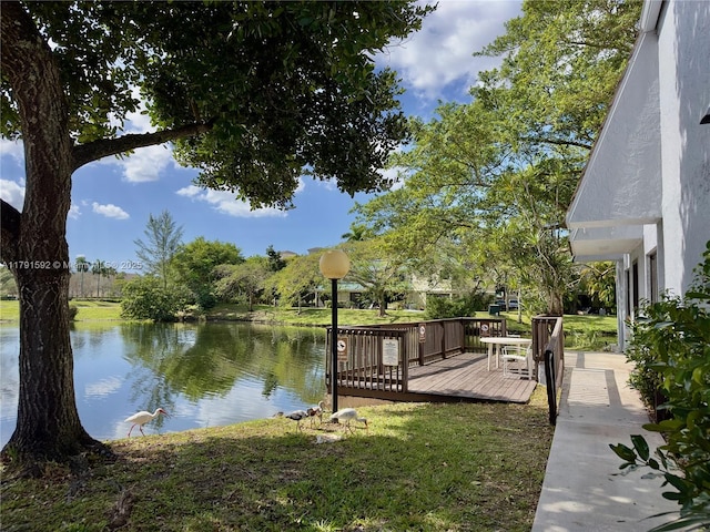 dock area featuring a lawn and a deck with water view