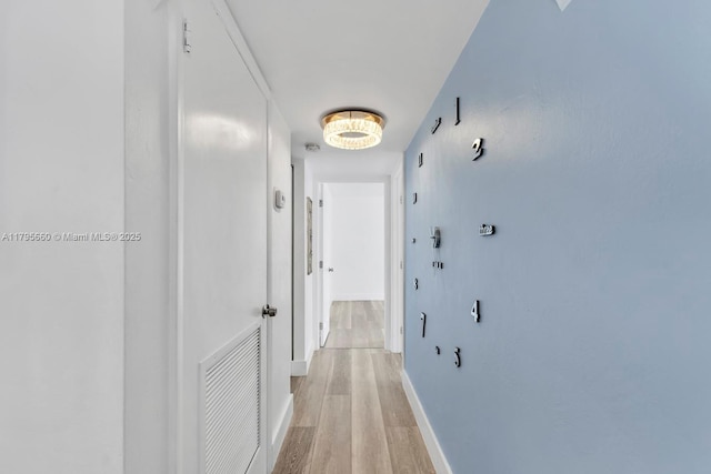 hall featuring visible vents, light wood-style flooring, and baseboards