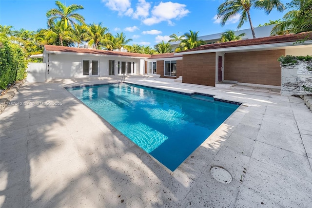 outdoor pool with french doors and a patio area