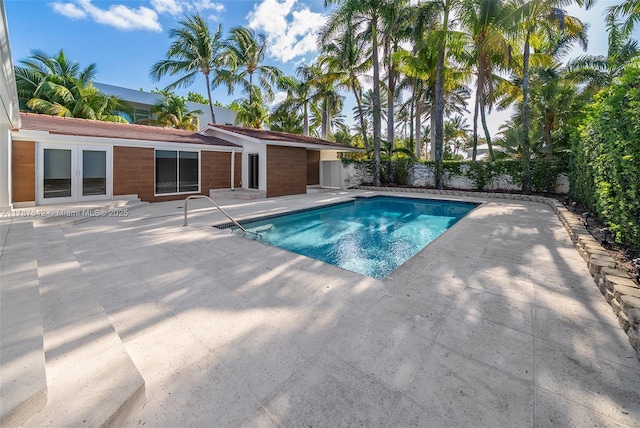 outdoor pool featuring french doors, fence, and a patio area