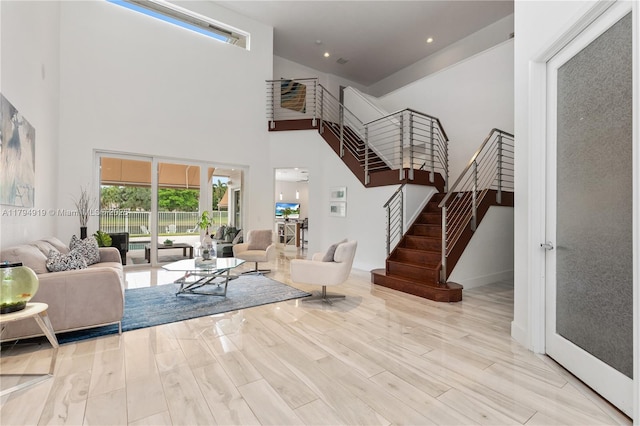 living area with baseboards, a towering ceiling, wood finished floors, and stairway