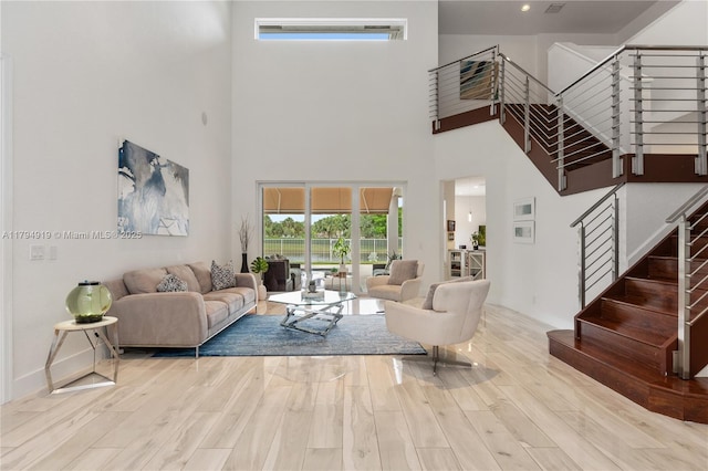 living room with stairs, wood finished floors, and a towering ceiling