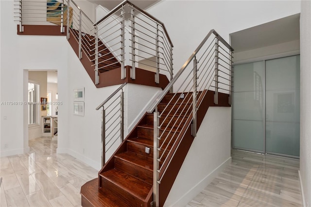 stairway featuring baseboards and a high ceiling