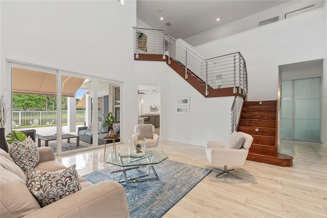 living room featuring wood finished floors, recessed lighting, stairs, and a high ceiling