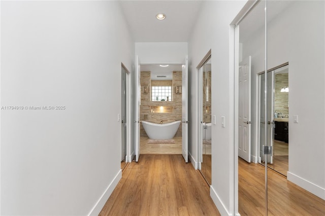hallway with baseboards, recessed lighting, and wood finished floors
