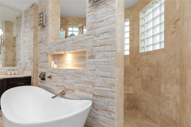 full bathroom with a freestanding tub, tile walls, vanity, and a healthy amount of sunlight