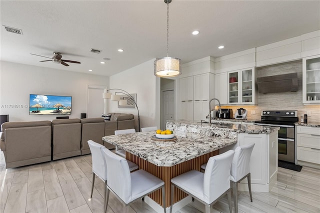 kitchen featuring a breakfast bar, extractor fan, range with two ovens, recessed lighting, and visible vents