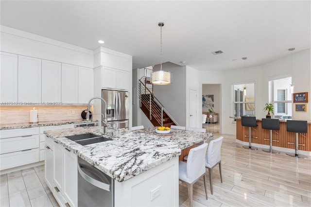 kitchen featuring appliances with stainless steel finishes, a sink, a kitchen island with sink, recessed lighting, and visible vents